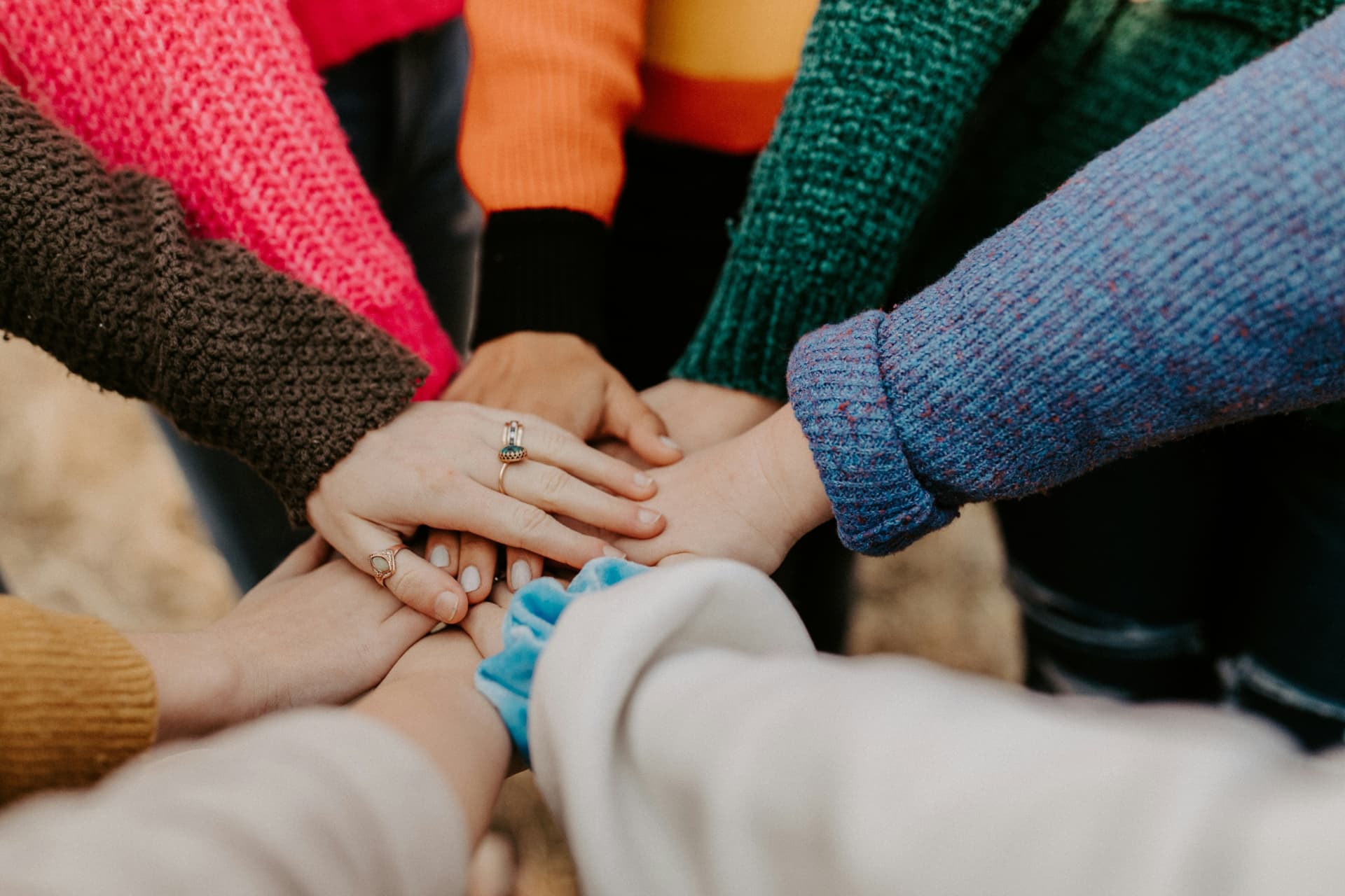 A group of young people placing their hands together in a circle
