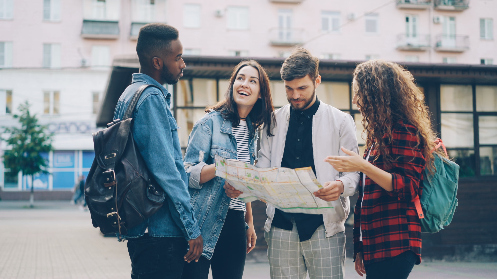 Four young people standing outdoors looking at a map together